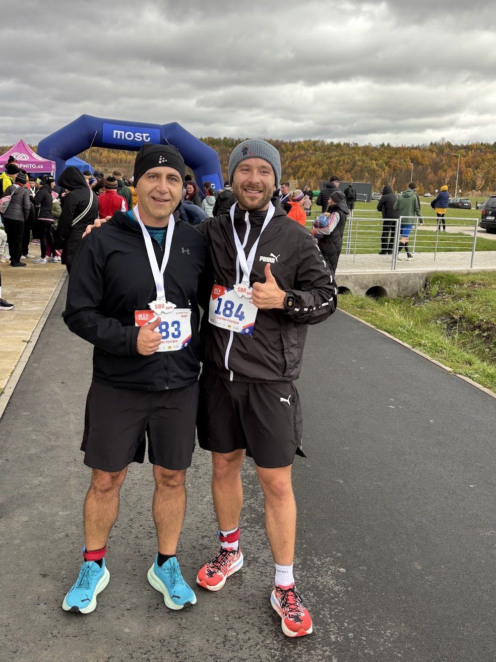 Dva trkača s medaljama stoje jedan do drugoga vani nakon sportskog događaja